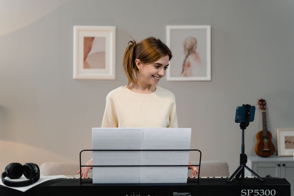 A young woman plays piano in a cozy home studio, captured with a modern camera angle.