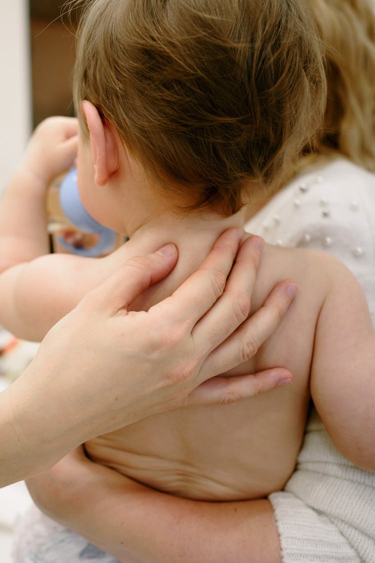 Person Holding A Baby On His Back