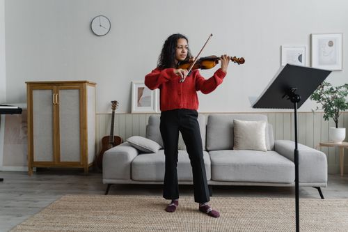Free Young woman practicing violin in stylish living room, creating an artistic and musical atmosphere. Stock Photo