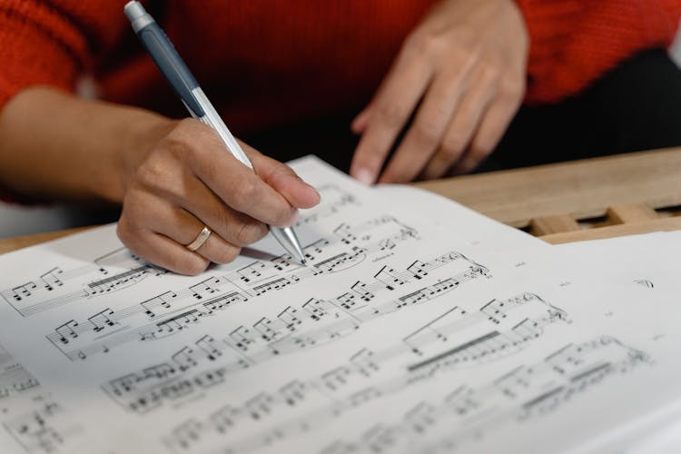 A Person Writing On A Sheet Music 