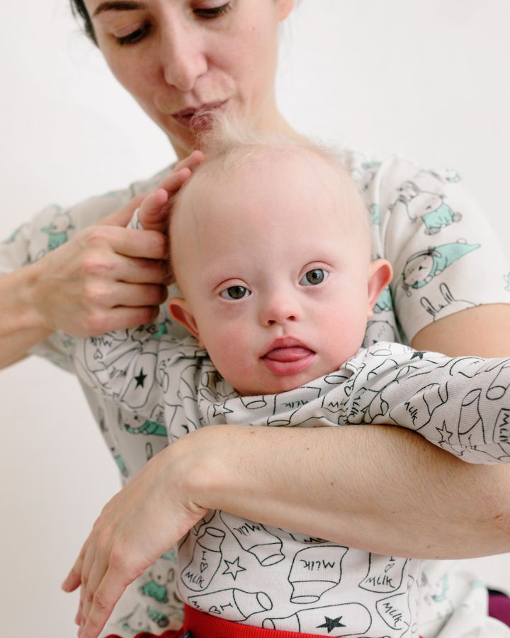 Mother holding her young child with Down syndrome with care and affection