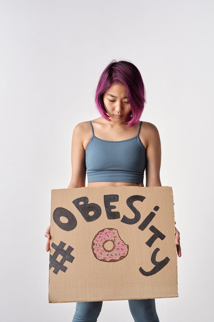 A Woman In Activewear Holding A Slogan About Obesity