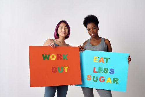 Free Two women holding motivational posters promoting healthy lifestyle changes against a white background. Stock Photo