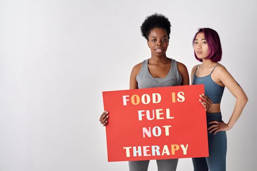 Women Holding Cardboard with Food Related Slogan