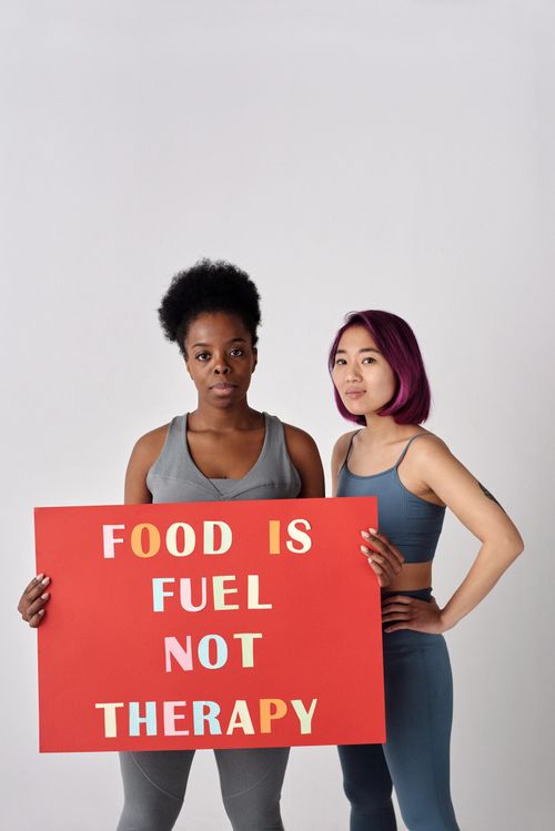 Free Two women stand confident with a sign promoting healthy food habits in a studio setting. Stock Photo