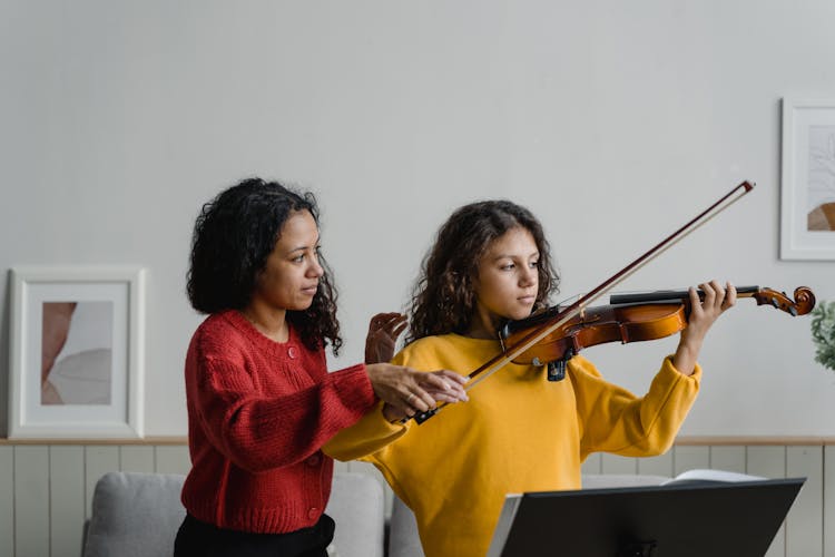 Woman Teaching The Girl How To Play The Violin 