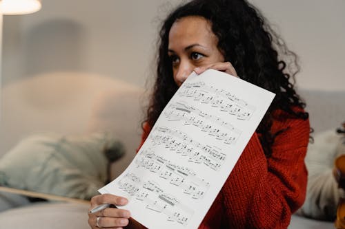 A Woman in Red Knitted Sweater Holding Sheet Music