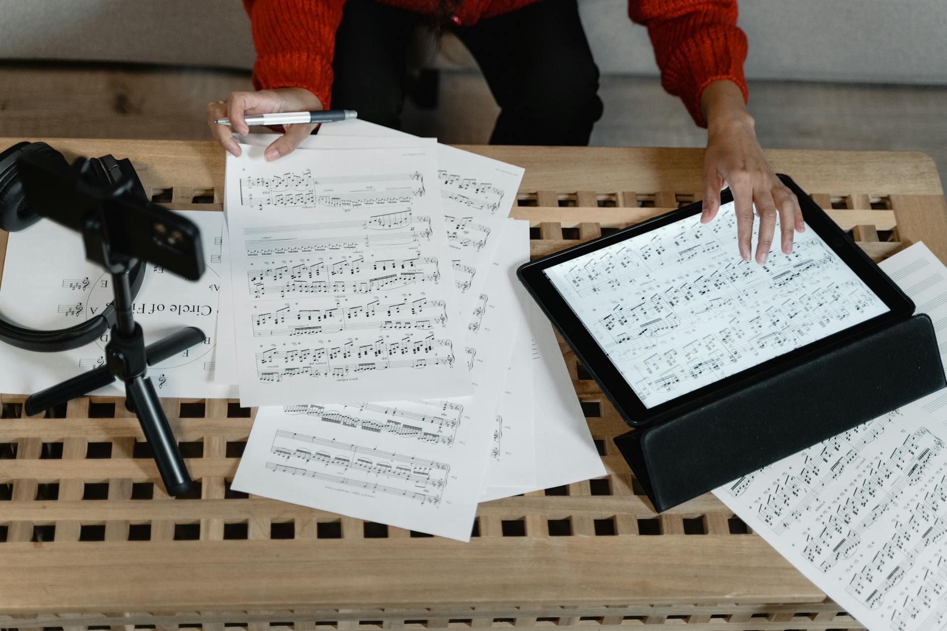 A musician analyzes sheet music on a tablet surrounded by paperwork. Ideal for m