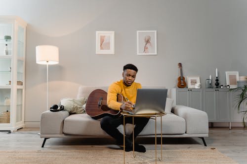 Man Holding a Guitar and Writing in the Living Room