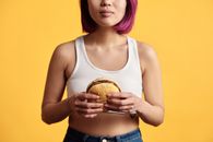 Person in White Tank Top Holding a Hamburger