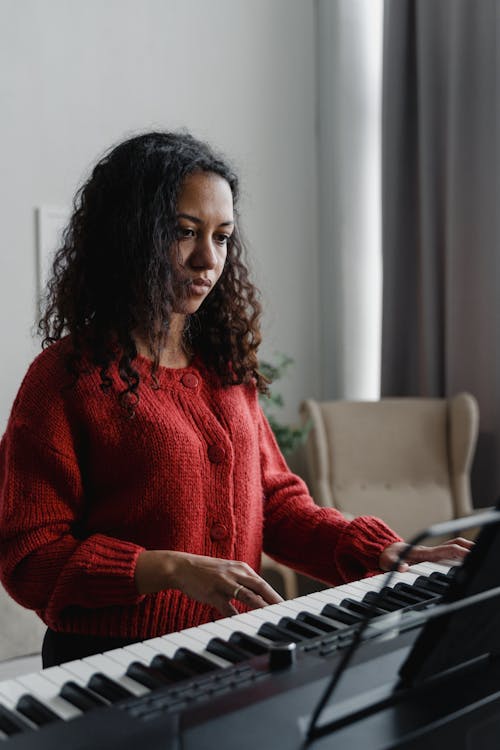 Curly Haired Woman Sitting Playing Digital Piano 