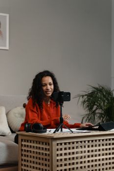 African American woman using smartphone to record video indoors, engaging content creation.