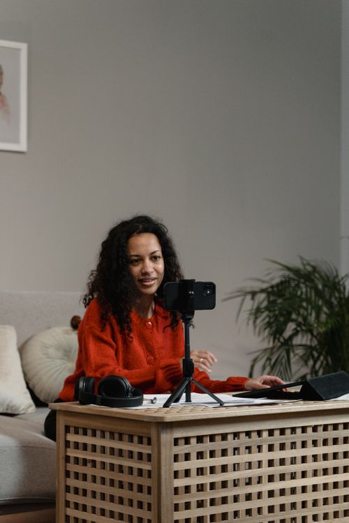 Free African American woman using smartphone to record video indoors, engaging content creation. Stock Photo