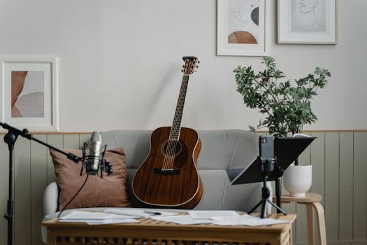 A peaceful home music studio with a guitar, microphone, and indoor plant setup for recording.