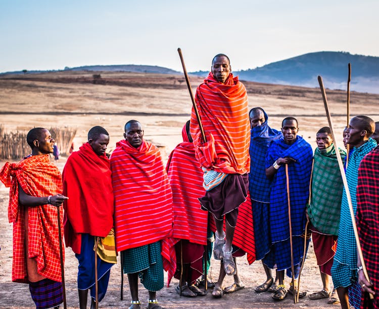 Photo Of Group Of Men Wearing Assorted Scarves Holding Sticks