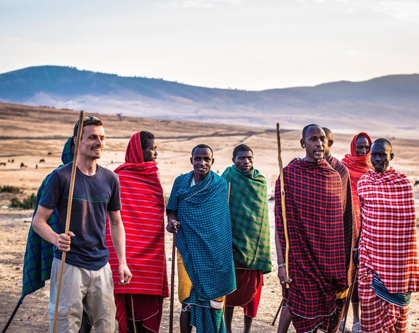 Randonneurs avec la tribu Masaï dans le paysage africain Un groupe de voyageurs et des membres de la tribu Masaï marchent ensemble sous le soleil dans un vaste paysage africain, symbolisant une immersion culturelle et naturelle authentique. Safari à pied Afrique