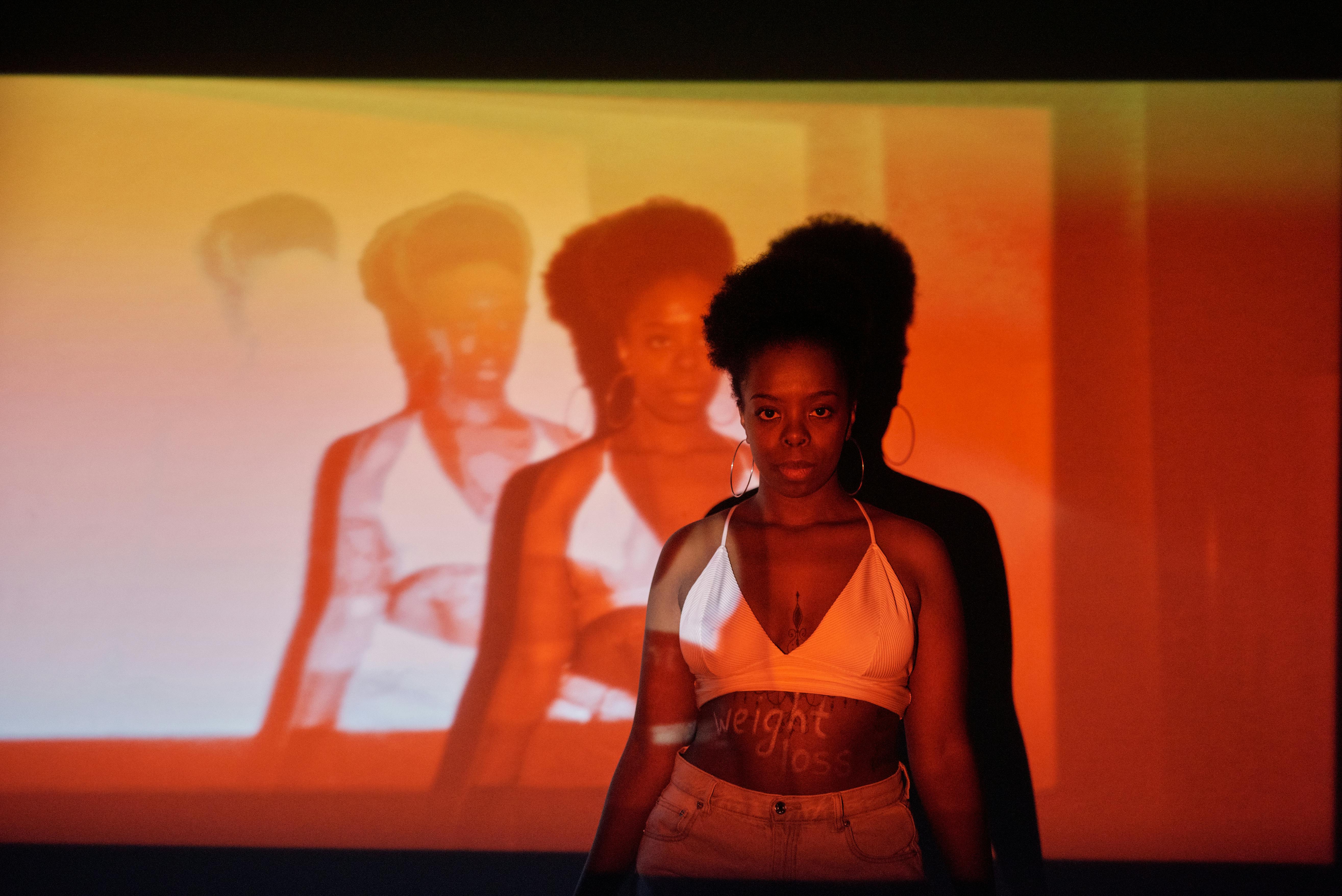 Artistic conceptual portrait of an African American woman with afro hair in moody lighting and projections.
