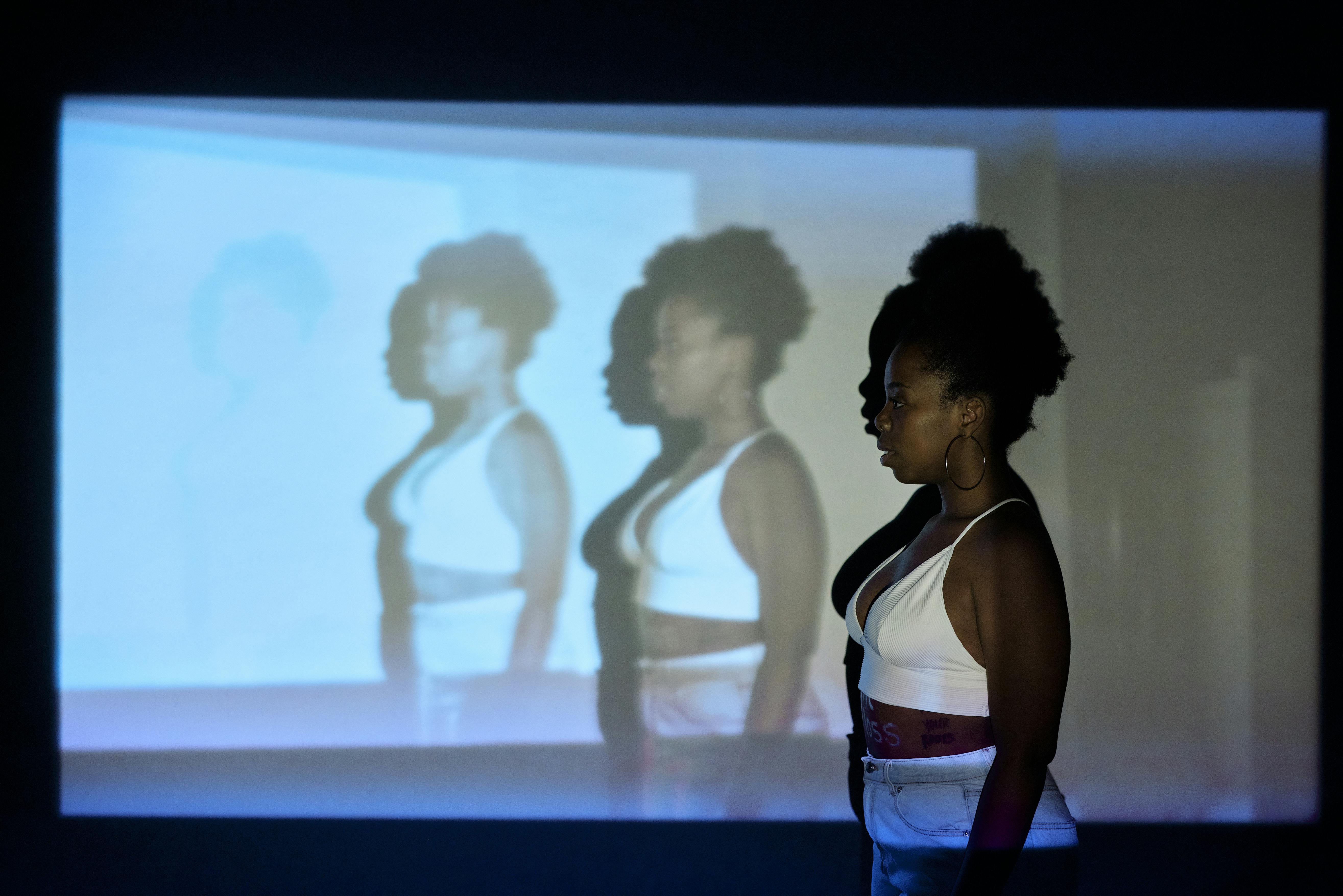 Artistic portrait of a black woman in a white crop top with projected images.