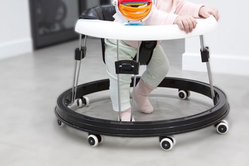 Baby learning to walk with a colorful baby walker indoors