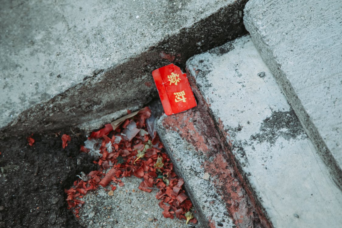 Free Close-up of a red envelope with Chinese characters on concrete steps with scattered debris. Stock Photo