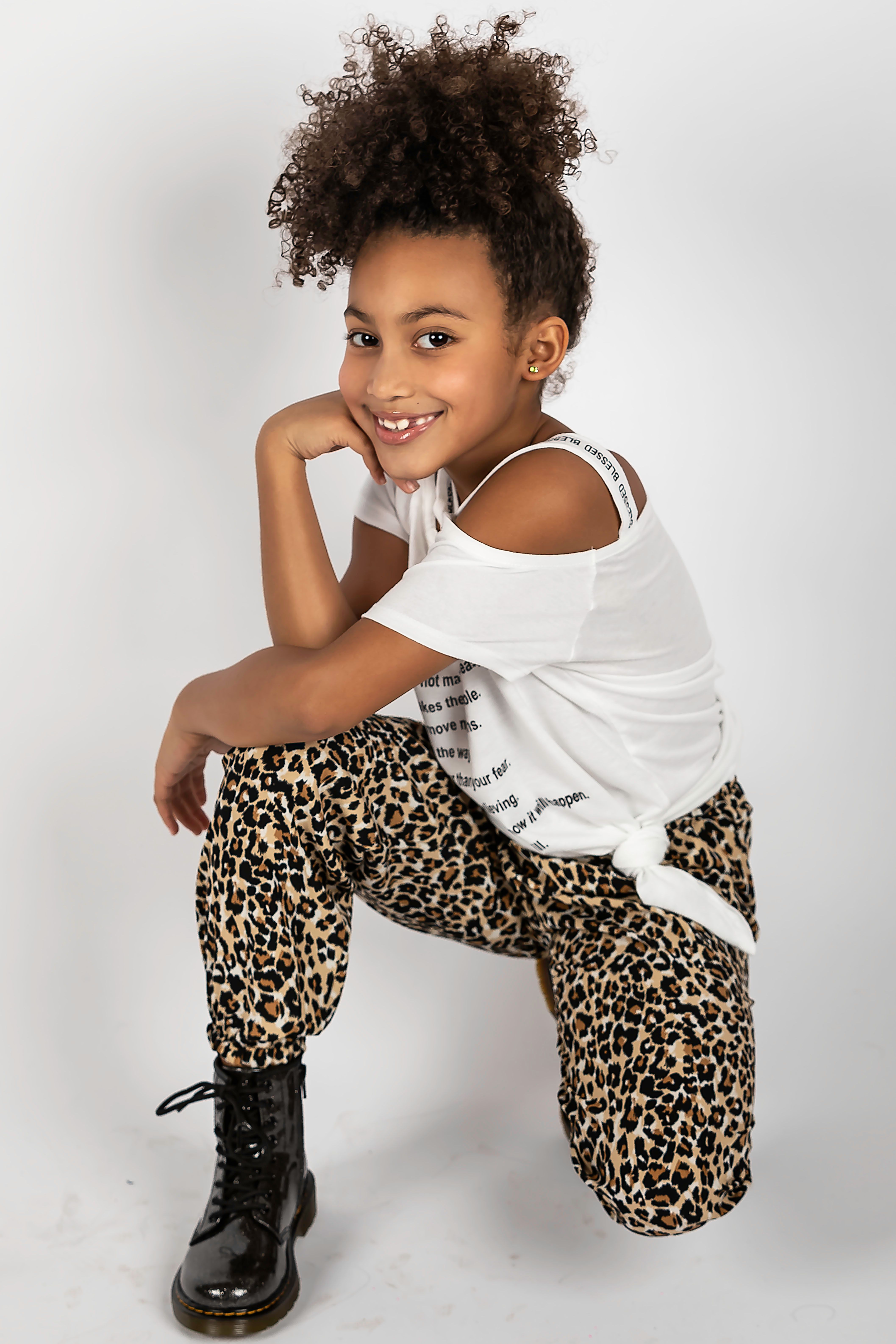 Cute African American girl posing in leopard print outfit during a studio photoshoot.