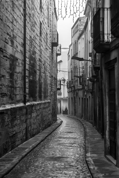 Free A narrow cobblestone alley in CT, Spain, captured in captivating black and white. Stock Photo
