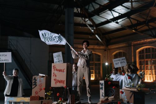Free Group of diverse activists holding peaceful protest signs in an industrial setting, promoting nonviolence. Stock Photo