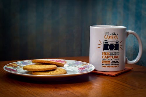 A Cup and Plate of Cookies on wooden Table