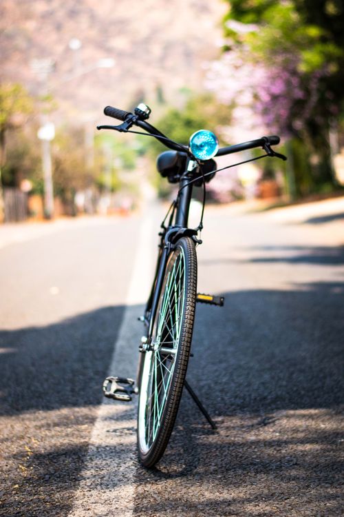Free A bicycle standing on an empty road, perfect for outdoor adventure and travel enthusiasts. Stock Photo
