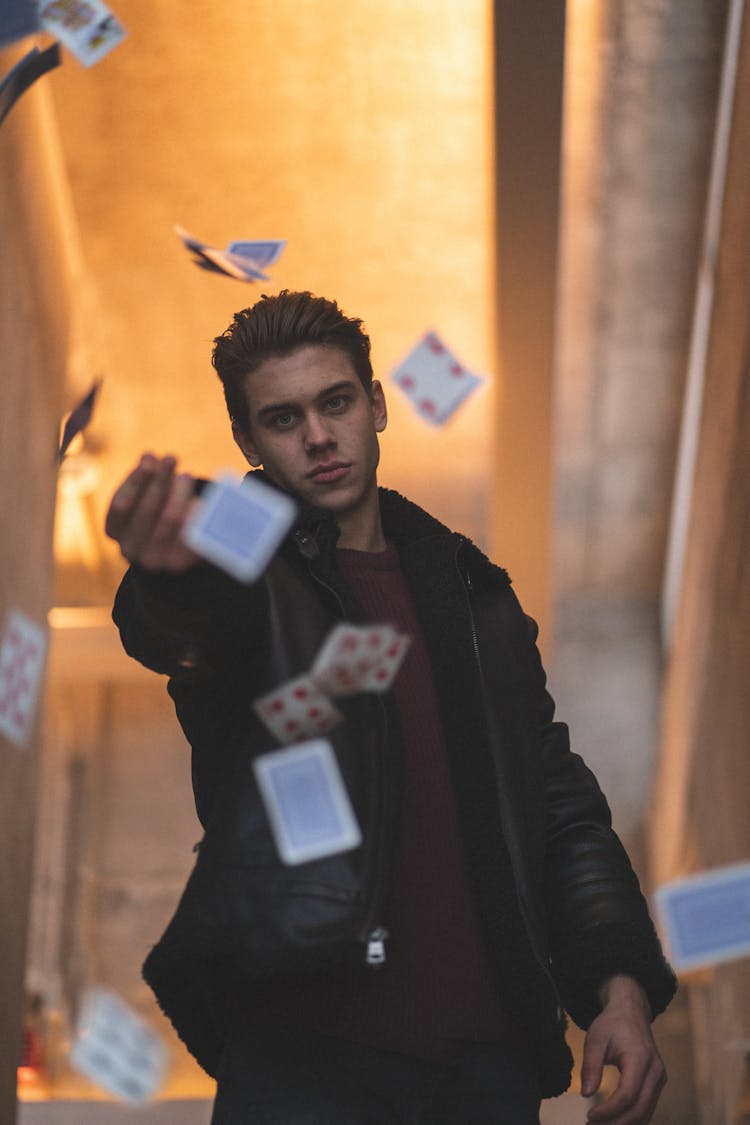 
A Man Wearing A Black Jacket Throwing Cards