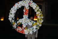 Floral peace symbol with vibrant flowers at night, embodying harmony and protest.