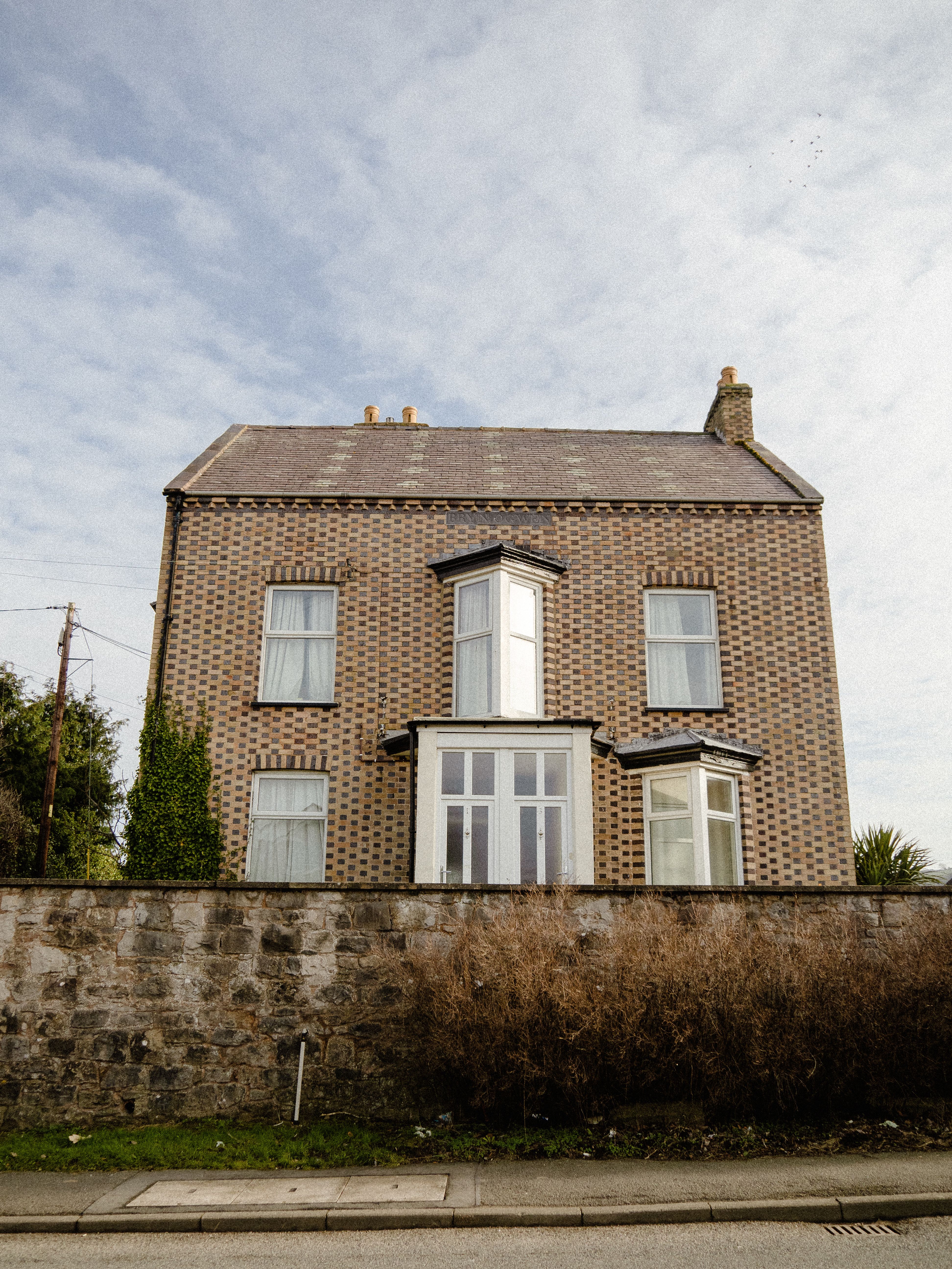 Handsome brick detached period house behind a stone wall