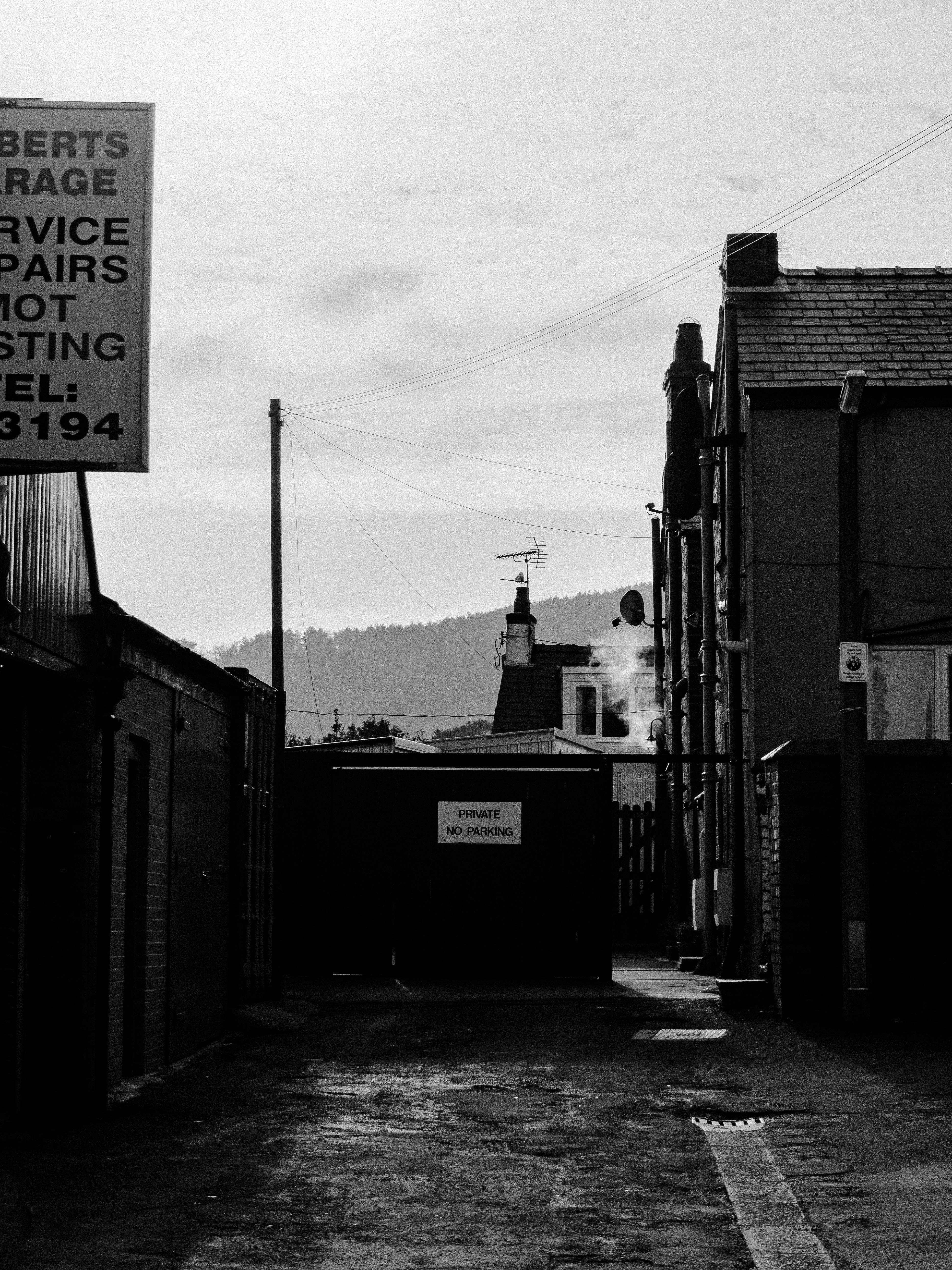 A black and white urban alleyway featuring garage signage and distant buildings.