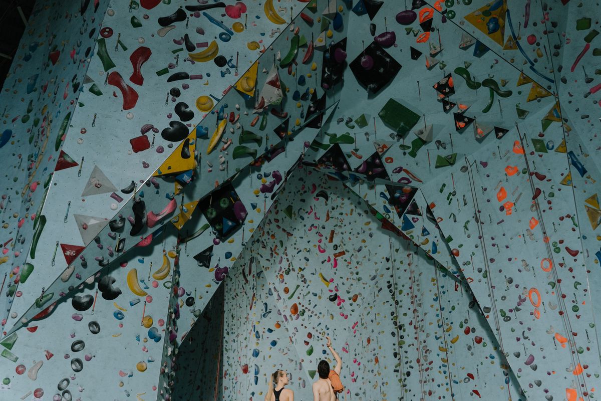 Deux personnes pratiquant l’escalade de bloc en salle, photo d’ambiance