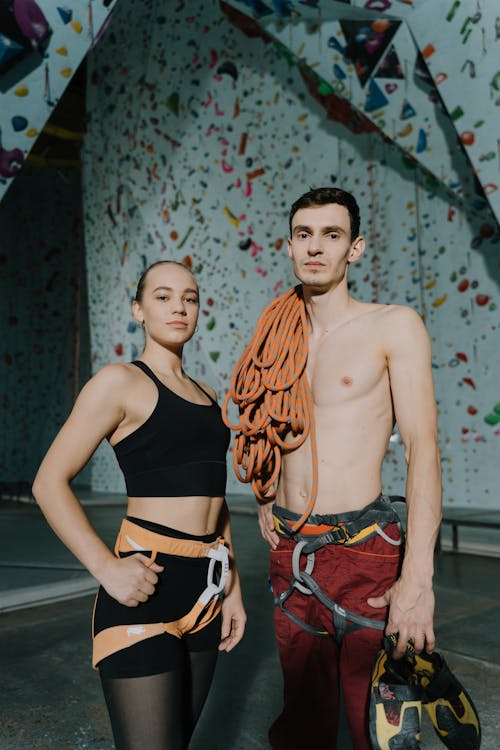 Free A Woman in Black Tank Top Standing Beside the Shirtless Man with Ropes on His Shoulder Stock Photo