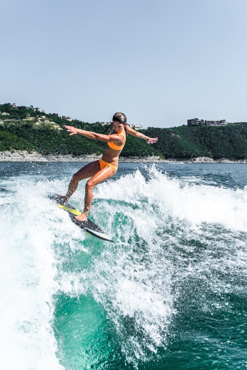 Woman in Orange Bikini Surfing on Sea Waves