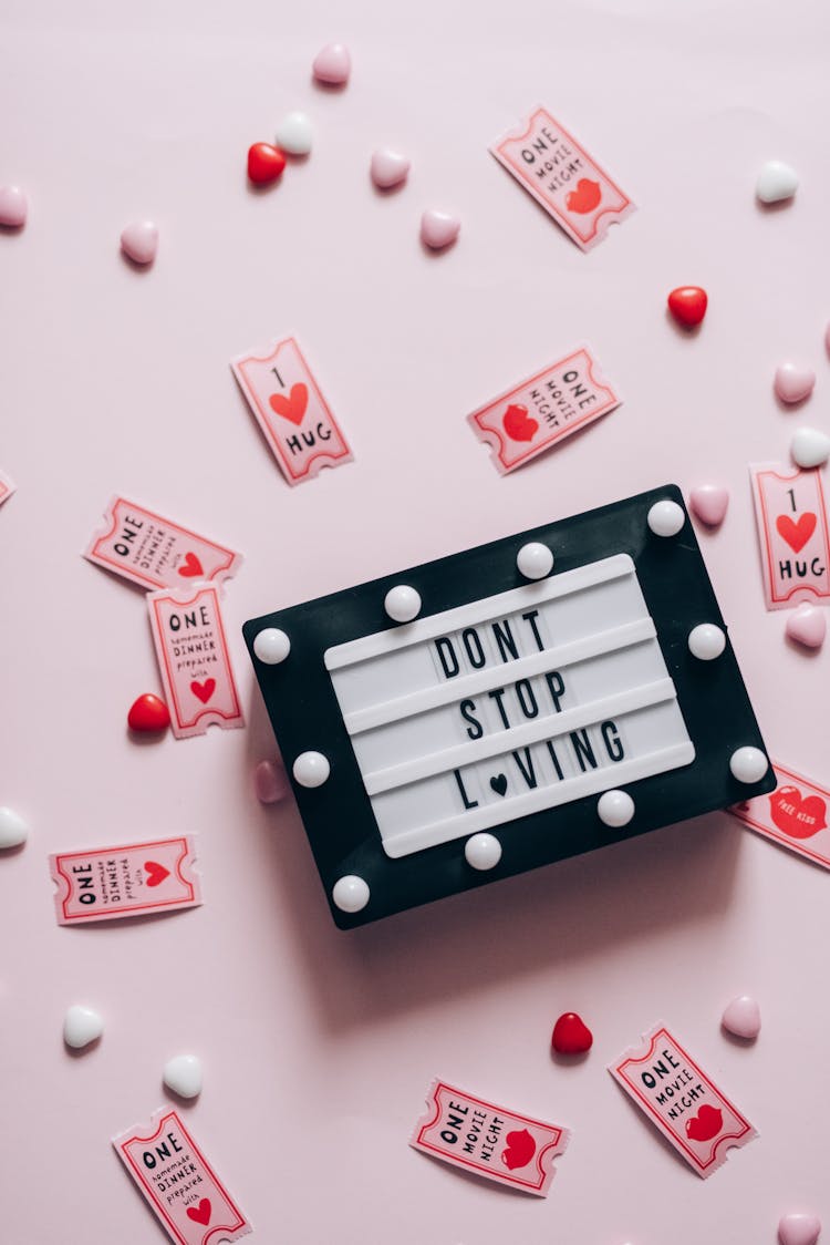 Flat Lay Of Don't Stop Loving Sign Surrounded By Movie Coupons