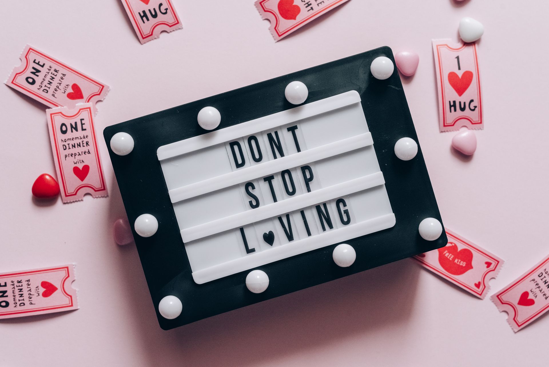 Lightbox with 'Don't Stop Loving' surrounded by hearts and love tokens on pink background.