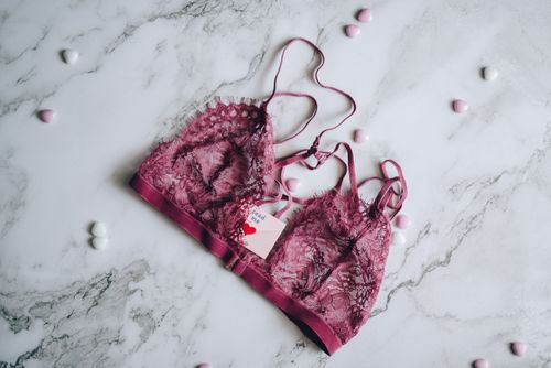 Free A stylish lace bra on a marble background surrounded by small hearts, captured in a flat lay style. Stock Photo