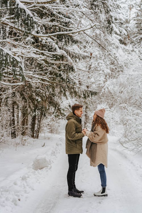 Couple Facing Each Other Under Snow Covered Trees