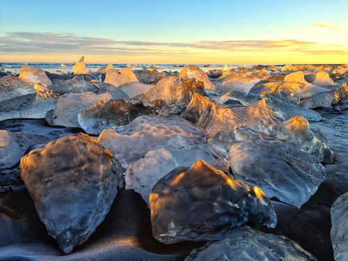 Free Captivating ice formations on a beach reflecting a vibrant sunset sky. Stock Photo