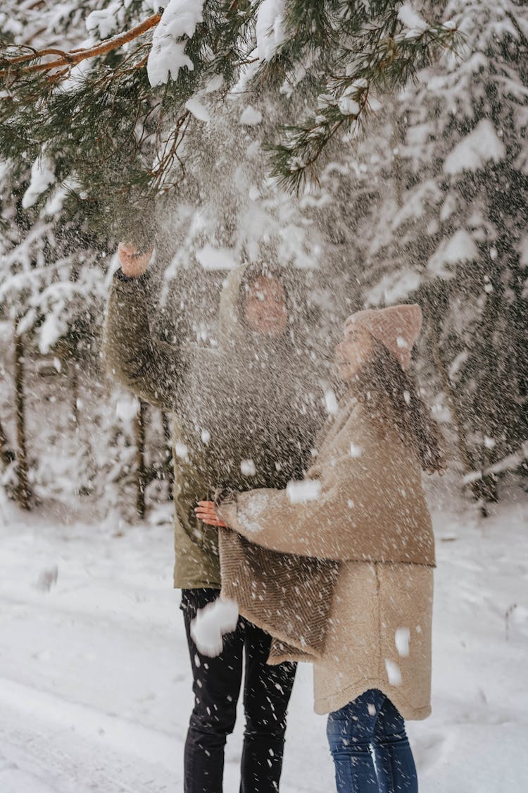 Couple In Warm Clothes Playing With Snow