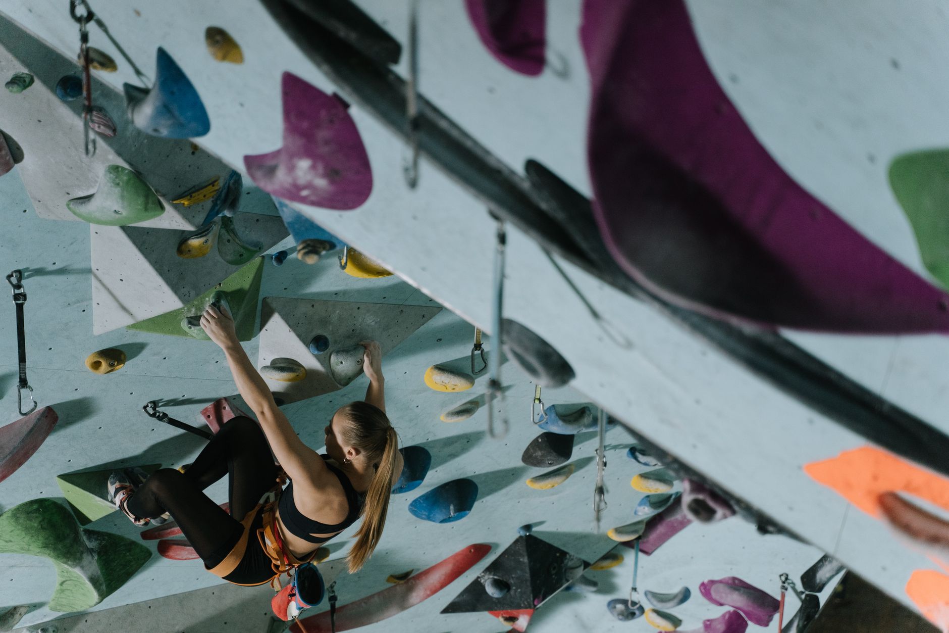 A woman demonstrates strength and agility on an indoor climbing wall.