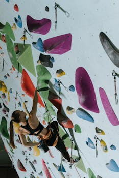 A woman practicing indoor rock climbing on a vibrant and colorful climbing wall.