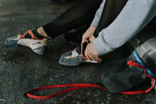 Close-up of a person putting on climbing shoes, preparing for an indoor climbing session.