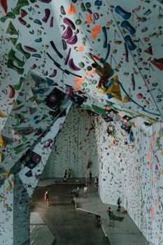 Indoor rock climbing gym featuring climbers scaling colorful walls.