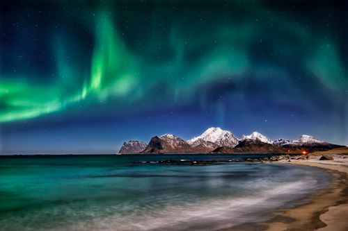Free Captivating aurora borealis over icy mountains by the sea under a starry night sky. Stock Photo
