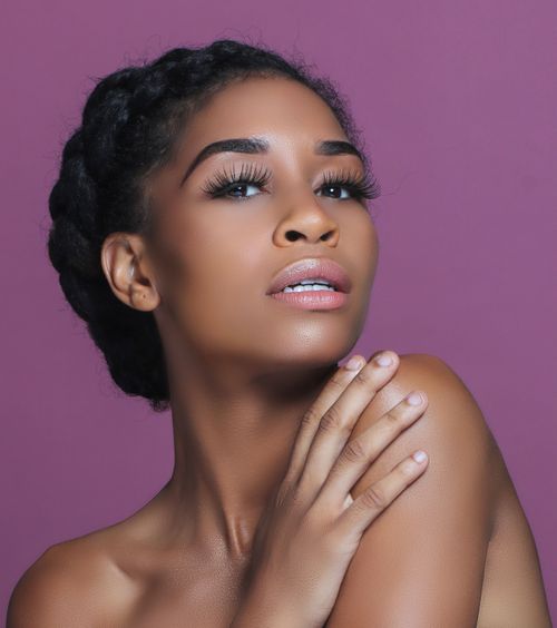 Free A beautiful portrait of a woman with smooth skin against a purple background, exuding confidence and grace. Stock Photo