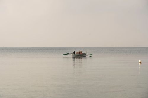 Free A group of people enjoy peaceful rowing on a calm sea with a captivating horizon. Stock Photo