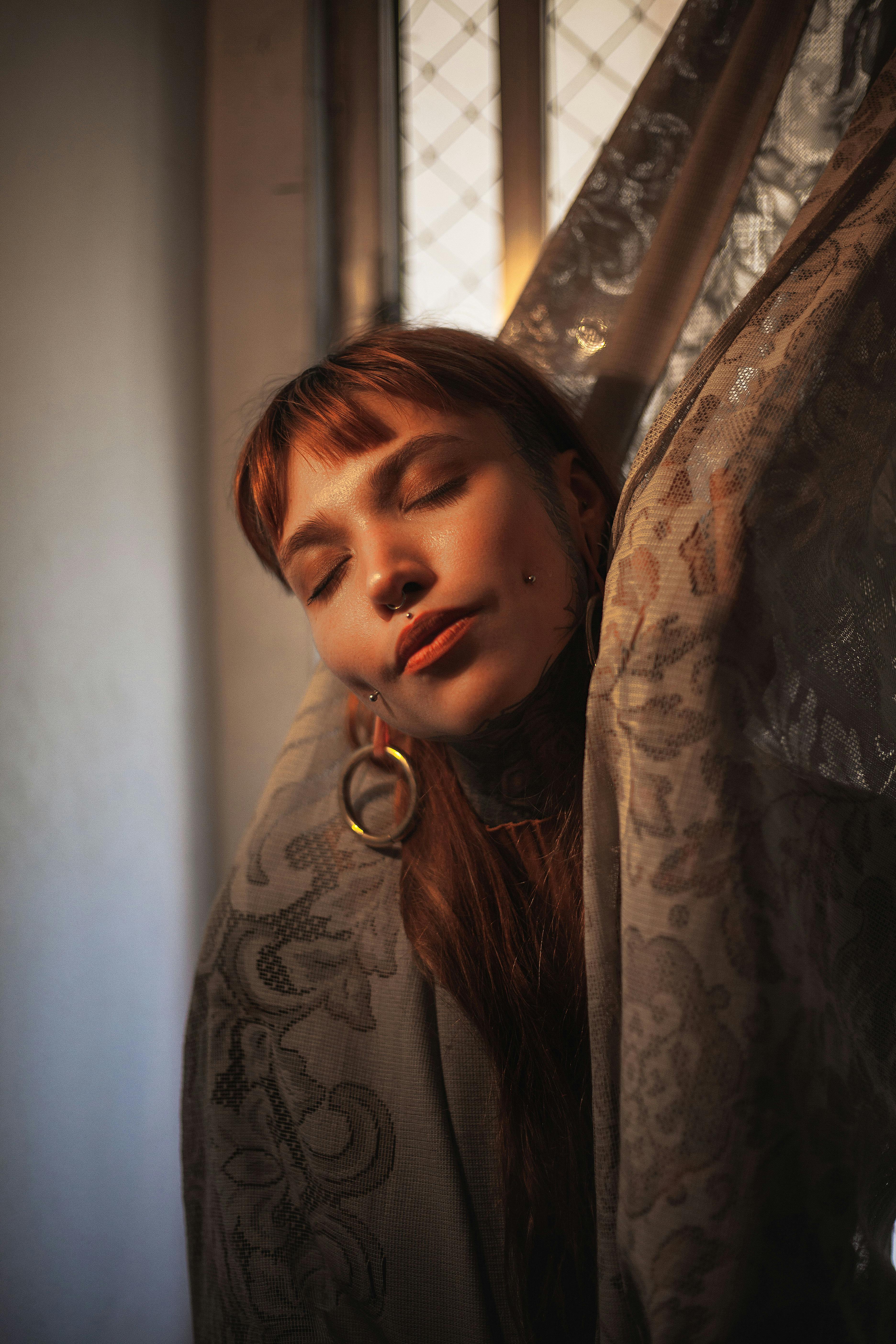 Serene portrait of a woman wrapped in a patterned curtain, softly lit, indoors in Dublin.